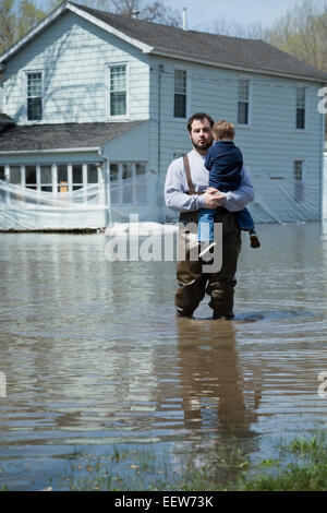 Mann mit Sohn stand vor Haus umgeben von Hochwasser Stockfoto