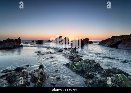 Sonnenuntergang über einem felsigen Strand an der Whitsand Bay in Cornwall Stockfoto