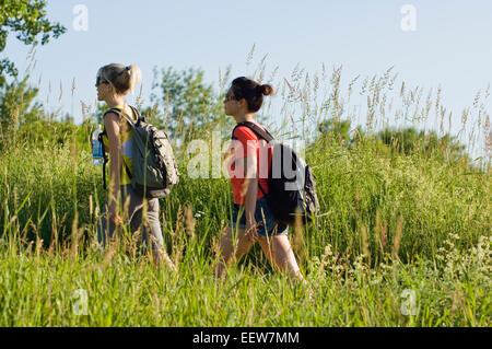 Zwei Freundinnen Wandern durch Rasen halten Wasser in Flaschen Stockfoto