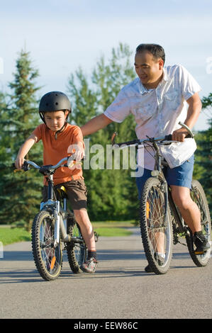 Vater und Sohn im Park mit dem Fahrrad Stockfoto