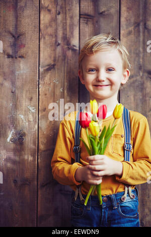 Kleiner Junge mit Rosenstrauss rote und gelbe Tulpen, Blick in die Kamera Stockfoto