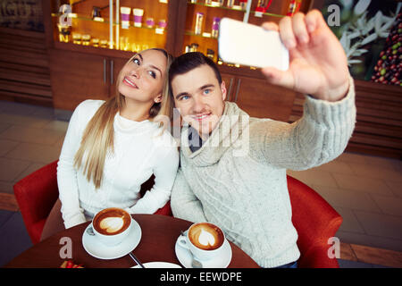 Junge Brautpaar in warme Pullover, wobei ihre Selfie im café Stockfoto