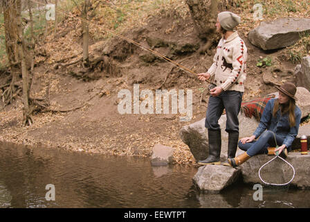 Junges Paar in einem Wald, in einem Fluss angeln. Stockfoto