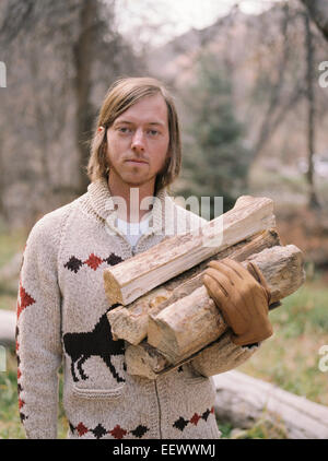 Junge blonde Mann mit Brennholz. Stockfoto