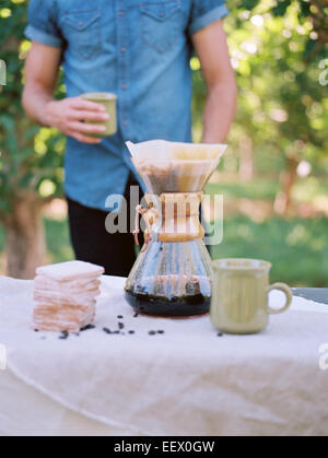 Obstgarten. Mann an einem Tisch stehend, Kaffee kochen. Stockfoto