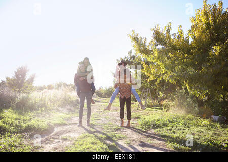 Apfelplantage. Zwei Paare zu Fuß entlang eines Pfades. Stockfoto