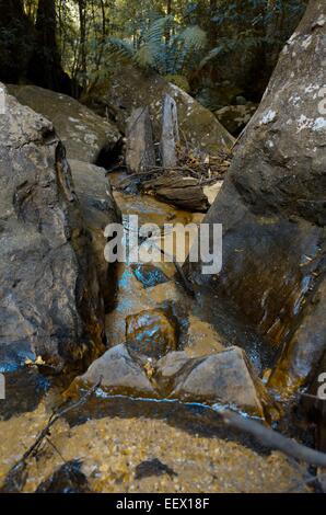 Strom des Wassers, das in der Mitte eine Schlucht von Findlingen Stockfoto