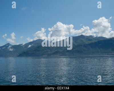 Seeufer-Szene am Comer See in Italien mit wolkenbestückten Bergen und blauem Himmel Stockfoto