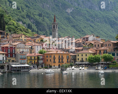 Die bunten Gebäude am See und Cafés von Varenna am Comer See in Italien mit Baum bedeckten Bergkulisse Stockfoto