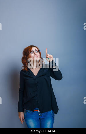 Europäische Erscheinung rothaarige Mädchen mit Brille zeigt eine Hand, Stockfoto