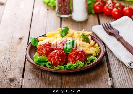 Fleischbällchen in Tomatensauce mit Pommes frites Stockfoto