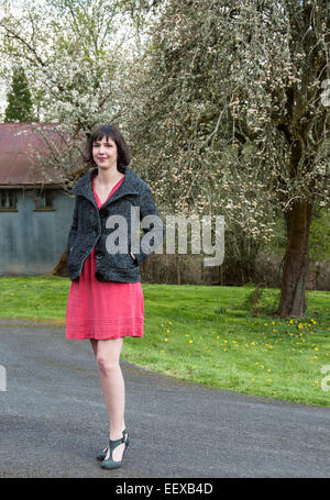 Eine Frau stand vor einer Blüte Birnbaum in die Kamera schaut Stockfoto