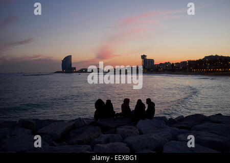 Barcelona, Spanien. 22. Januar 2015. Eine Gruppe von Menschen ruhen auf einem Wellenbrecher beim Sonnenuntergang auf der mediterranen Küste von Barcelona, Spanien. Bildnachweis: Jordi Boixareu/Alamy Live-Nachrichten Stockfoto