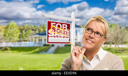 Attraktive junge Frau mit Bleistift vor für Verkauf Immobilien Zeichen und Haus verkauft. Stockfoto