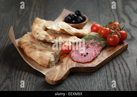 Antipasti mit Salami, Oliven, Tomaten und Brot auf Holztisch Stockfoto