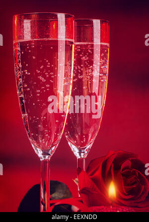 Valentine Tag Abendessen, zwei elegante Glas Champagner verziert mit roten Rosen und Kerzen, romantische Stillleben, Liebe und Leidenschaft Stockfoto