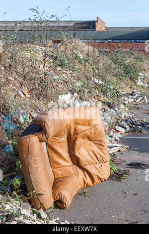 Kippen Fliegen. Die illegale Verklappung von einem Ledersessel, Abfall und anderen Müll auf einem Gehsteig am Rande einer Stadt. Nottingham, England, Großbritannien Stockfoto