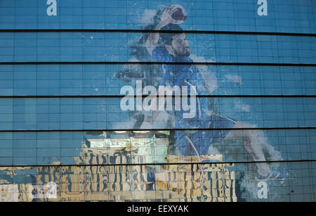 Ein Gebäude aus der inneren Stadt Doha spiegelt sich auf einer Glasfront einer Bank, aufbauend auf die eine Werbung für den Handball ist angebracht bei der Herren Handball-WM im Hilton Hotel Doha, Katar, 21. Januar 2015. Foto: Axel Heimken/dpa Stockfoto