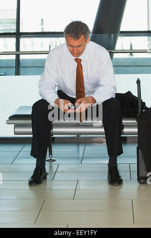 Kaufmann im Flughafen mit persönlicher digitaler Assistent Stockfoto