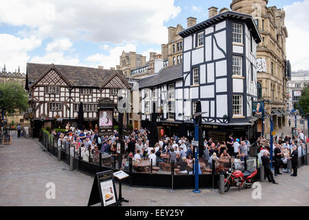 Besetzt Das alte Fachwerkhaus aus dem 16. Jahrhundert Wellington Inn 1552 städtischen Pub mit einer Menge von Menschen in den Biergarten. Manchester, England, Großbritannien, Großbritannien Stockfoto