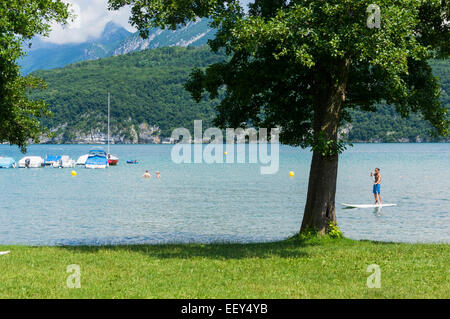 Lac d’Annecy, Haute-Savoie, Frankreich, Europa. Mann auf einem Stand Up Paddle-Brett mit Schwimmern im Sommer Stockfoto