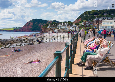 Seaside, Großbritannien – Menschen, die in Liegestühlen an der Küste von Sidmouth, East Devon, England sitzen Stockfoto