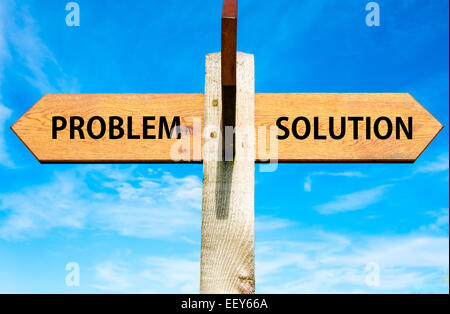 Wegweiser aus Holz mit zwei entgegengesetzte Pfeile über klaren, blauen Himmel, Problem versus Lösung Nachrichten, Probleme lösen Konzeptbild Stockfoto
