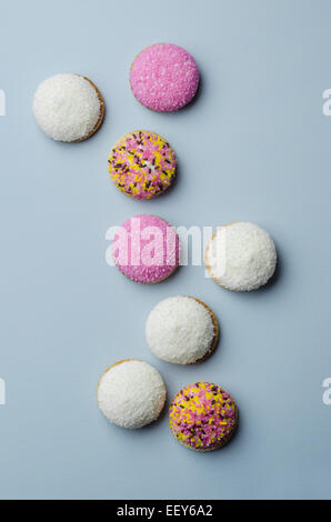 Marshmallow bunte Kekse, rosa Zucker und Kokos-Streusel auf blauem Hintergrund, über Ansicht Stockfoto