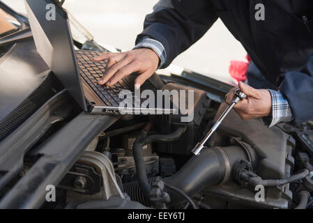 Mechaniker mit Laptop während der Reparatur Auto Stockfoto