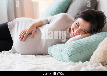 Schwangere Frau im Bett lächelnd Stockfoto