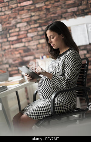 Schwangere Frau, die im Büro arbeiten Stockfoto