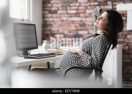 Schwangere Frau Entspannung im Büro Stockfoto