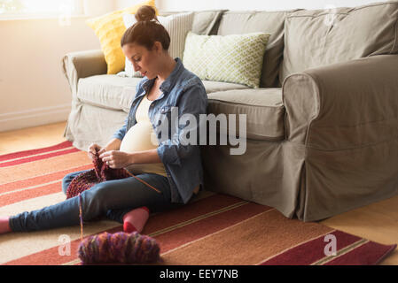 Schwangere Frau sitzen am Boden stricken Stockfoto