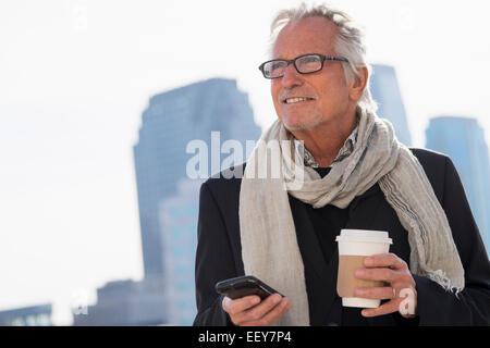 Mann in der Straße mit Kaffee und smartphone Stockfoto