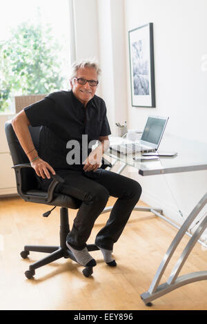 Porträt von lächelnden senior Mann sitzt im home-office Stockfoto