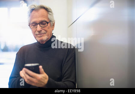 Ältere Mann in Büro Korridor und Text-messaging Stockfoto