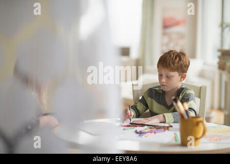 Junge (6-7) sitzen und zeichnen im Familienzimmer Stockfoto