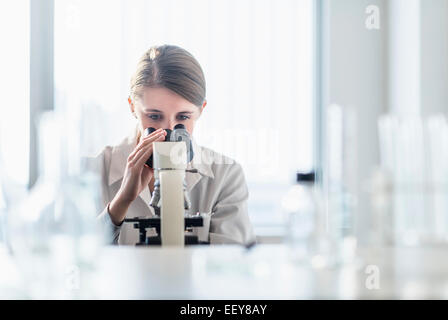 Weibliche Laborantin, die Analyse der Probe durch Mikroskop Stockfoto