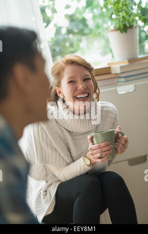 Lächelnde Frau sitzen und halten Becher Stockfoto