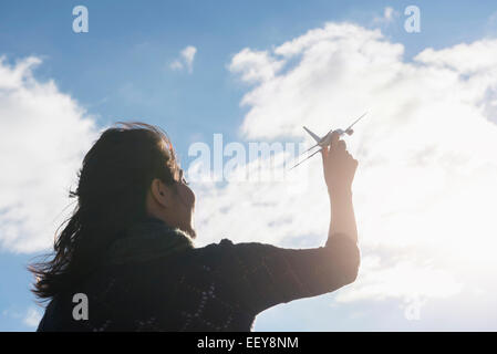 Junge Frau mit Modellflugzeug gegen bewölktem Himmel Stockfoto