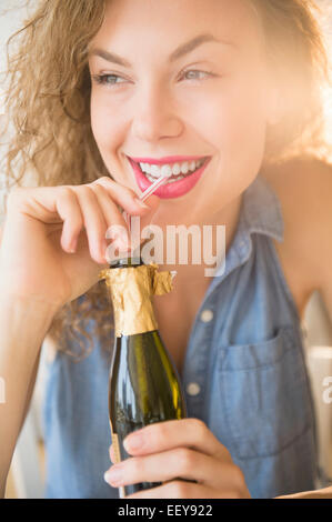 Fröhliche junge Frau schlürfen Champagner Flasche Stockfoto