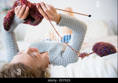 Junge Frau liegend und stricken Stockfoto