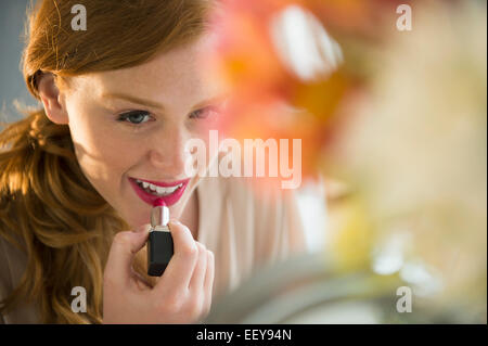 Junge Frau Auftragen von Lippenstift Stockfoto