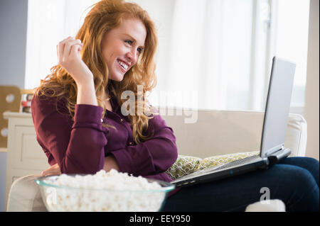 Junge Frau Essen Popcorn und mit laptop Stockfoto