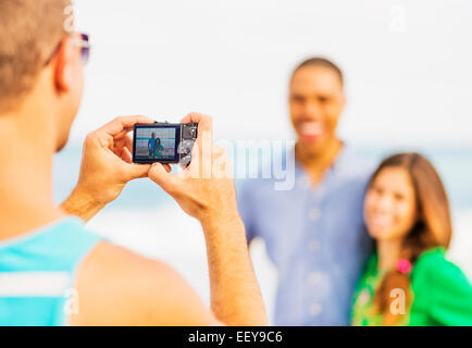 Junger Mann nehmen Foto des Paares am Strand Stockfoto