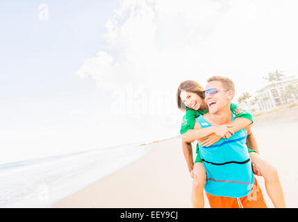 USA, Florida, Jupiter, junges Paar Huckepack Reiten am Strand zu tun Stockfoto