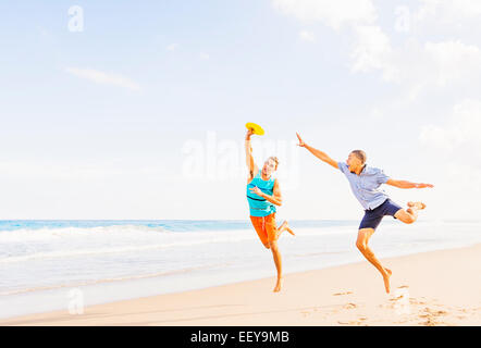 USA, Florida, Jupiter, junge Männer spielen Kunststoffscheibe am Strand Stockfoto