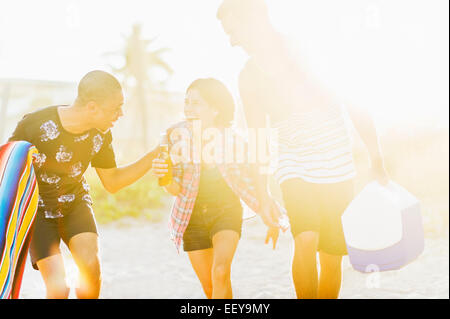 USA, Florida, Jupiter, junge Menschen zu Fuß am Strand, trinken Bier bei Sonnenuntergang Stockfoto