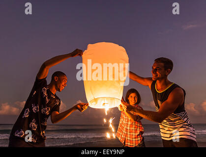 Junge Menschen mit beleuchteter Laterne am Strand Stockfoto