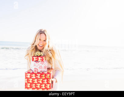 Porträt der lächelnde Frau hält präsentiert am Strand Stockfoto